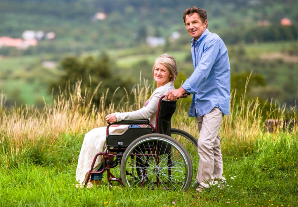 an elder woman in a wheelchair with an elder man standing
